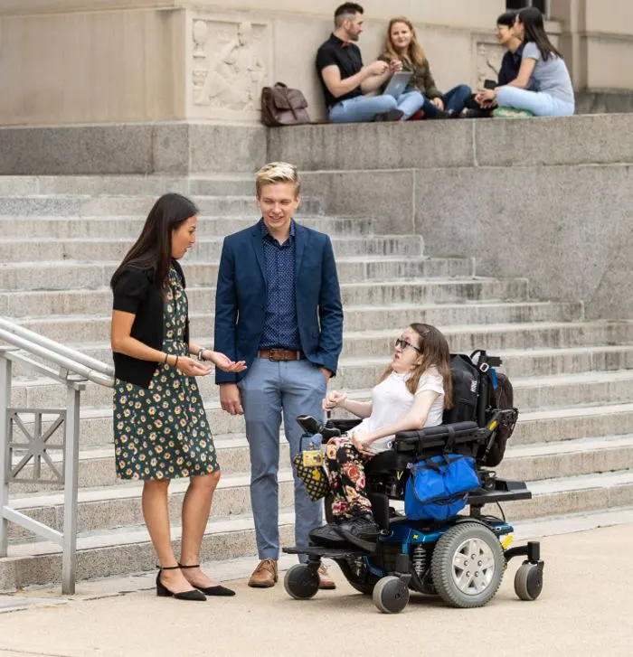 Three people talking on the steps of Angell Hall