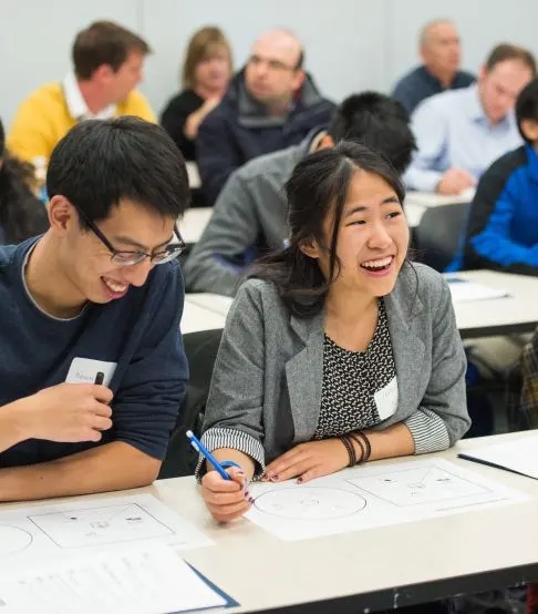 Two people laughing while working on an assignment